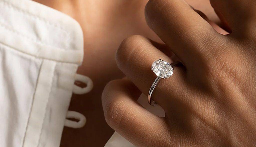 Diamond engagement ring with sparkling stones on a woman's hand.