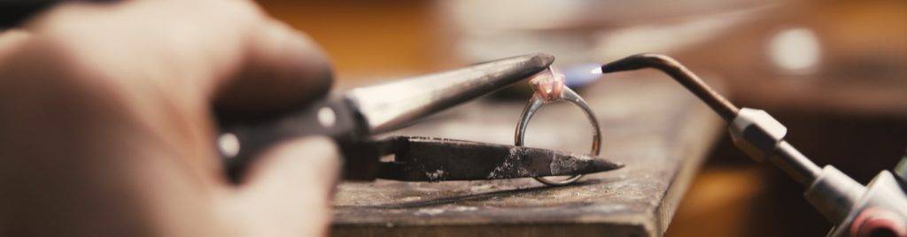 Close-up of ring repair process with tools and flame on workbench, demonstrating professional jewellery services in Australia.